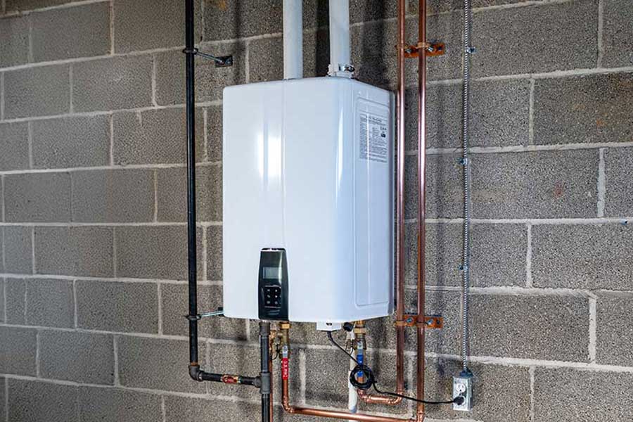 Tankless water heater mounted on a cinder block wall with copper piping